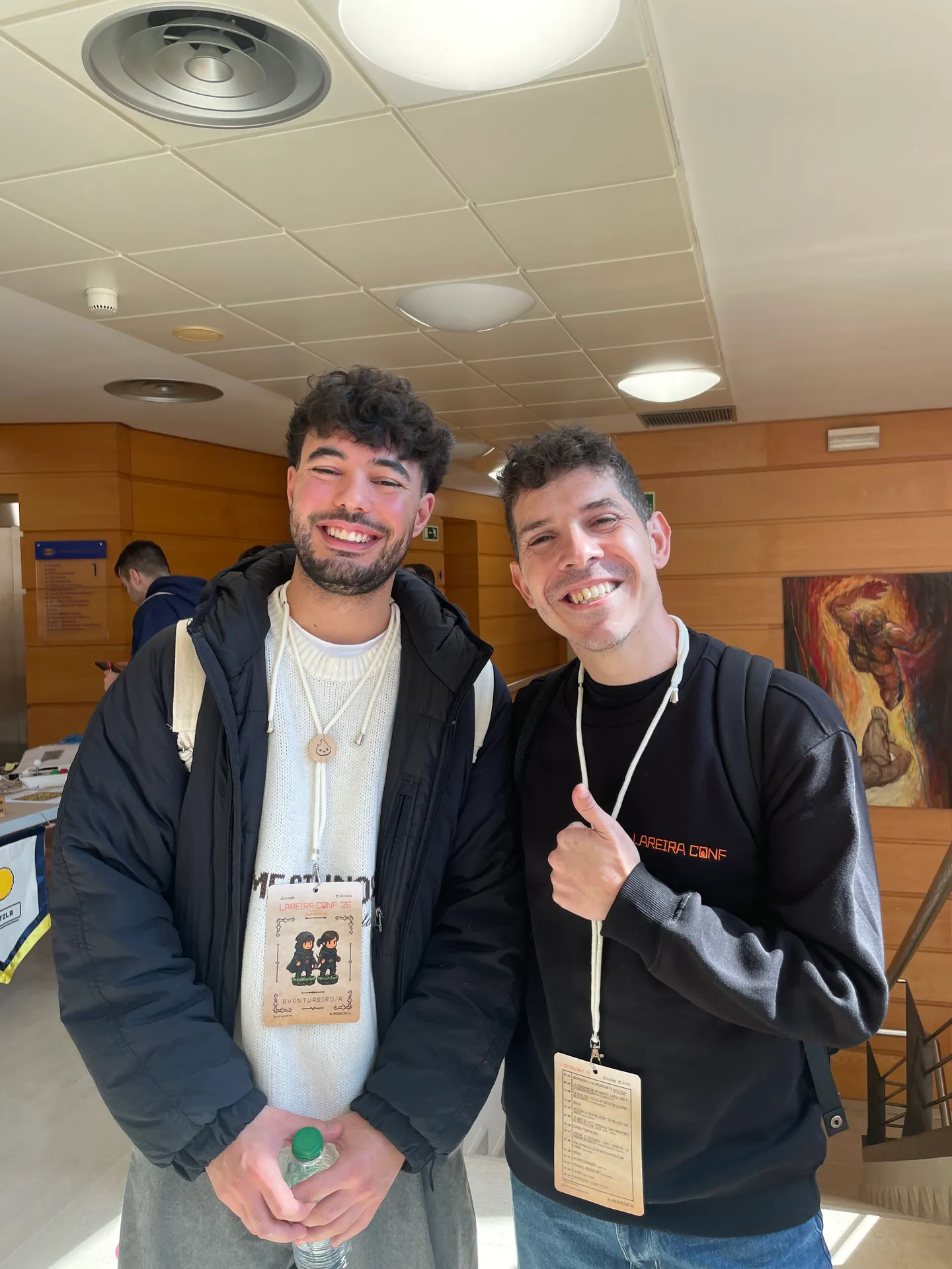 Raúl and midudev smiling at a conference, both wearing badges